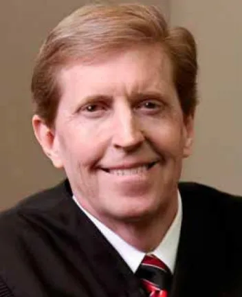 Smiling male judge in black robe with red-striped tie